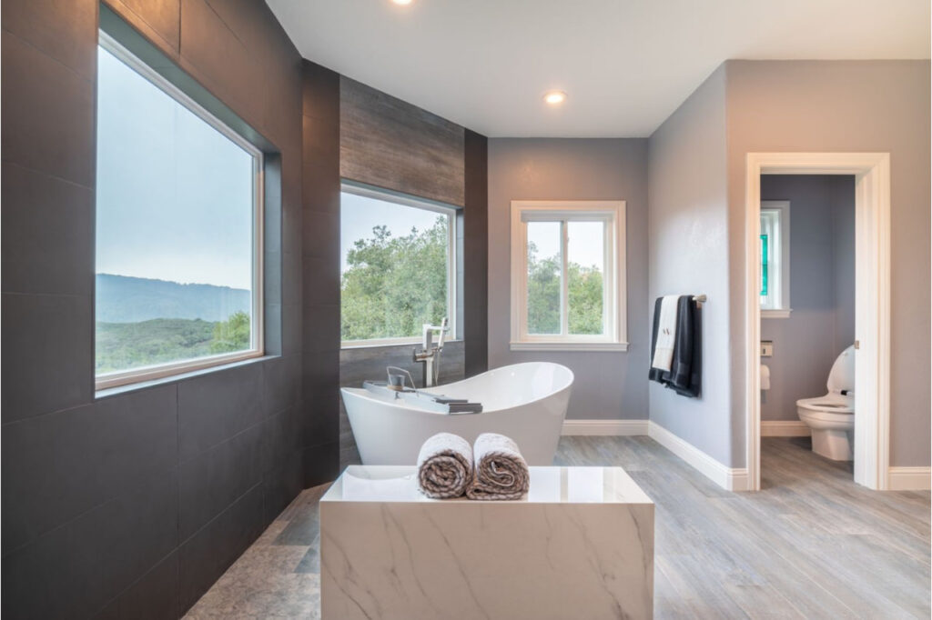 Bathroom remodeling in Los Gatos showcasing freestanding tub with warm wood accents and panoramic window views