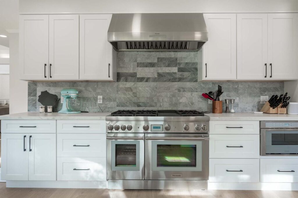Vista Del Mar kitchen in Los Gatos with professional-grade range, tile backsplash, custom white cabinetry, and engineered white oak flooring