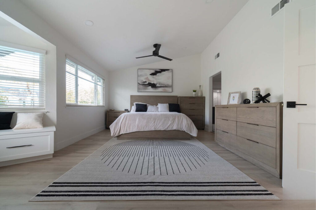 Serene full home remodel San Jose primary bedroom featuring neutral tones with modern ceiling fan and elegant bedding