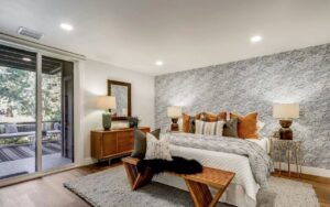 Professional home addition contractor in San Jose creates luxurious master bedroom featuring dramatic stone accent wall and premium finishes