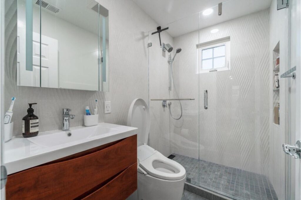Home remodeling bathroom with wood vanity, matte black fixtures, freestanding tub, and glass shower enclosure