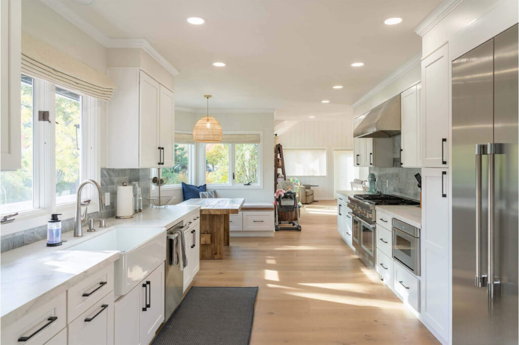Kitchen contractors in San Francisco create minimalist layout with light wood peninsula, white cabinetry, and integrated recessed lighting by ASL Remodeling