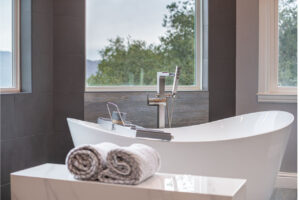 Stunning open concept bathroom design creating seamless indoor-outdoor living with modern black vanity and freestanding tub with garden views