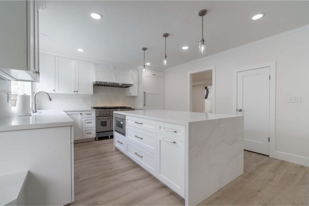 Clean minimalist design featuring crisp white shaker cabinets, sleek quartz countertops, modern gray island, and contemporary pendant lighting in bright open layout.